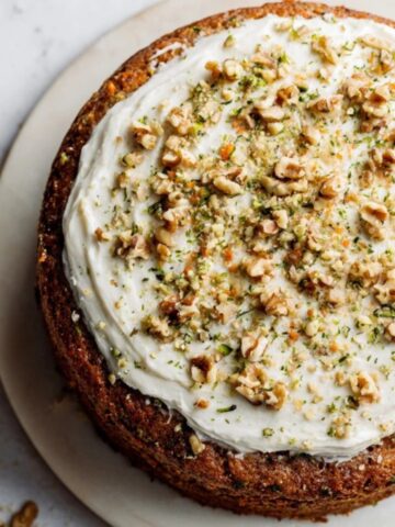 moist carrot zucchini cake with cream cheese frosting on white counter