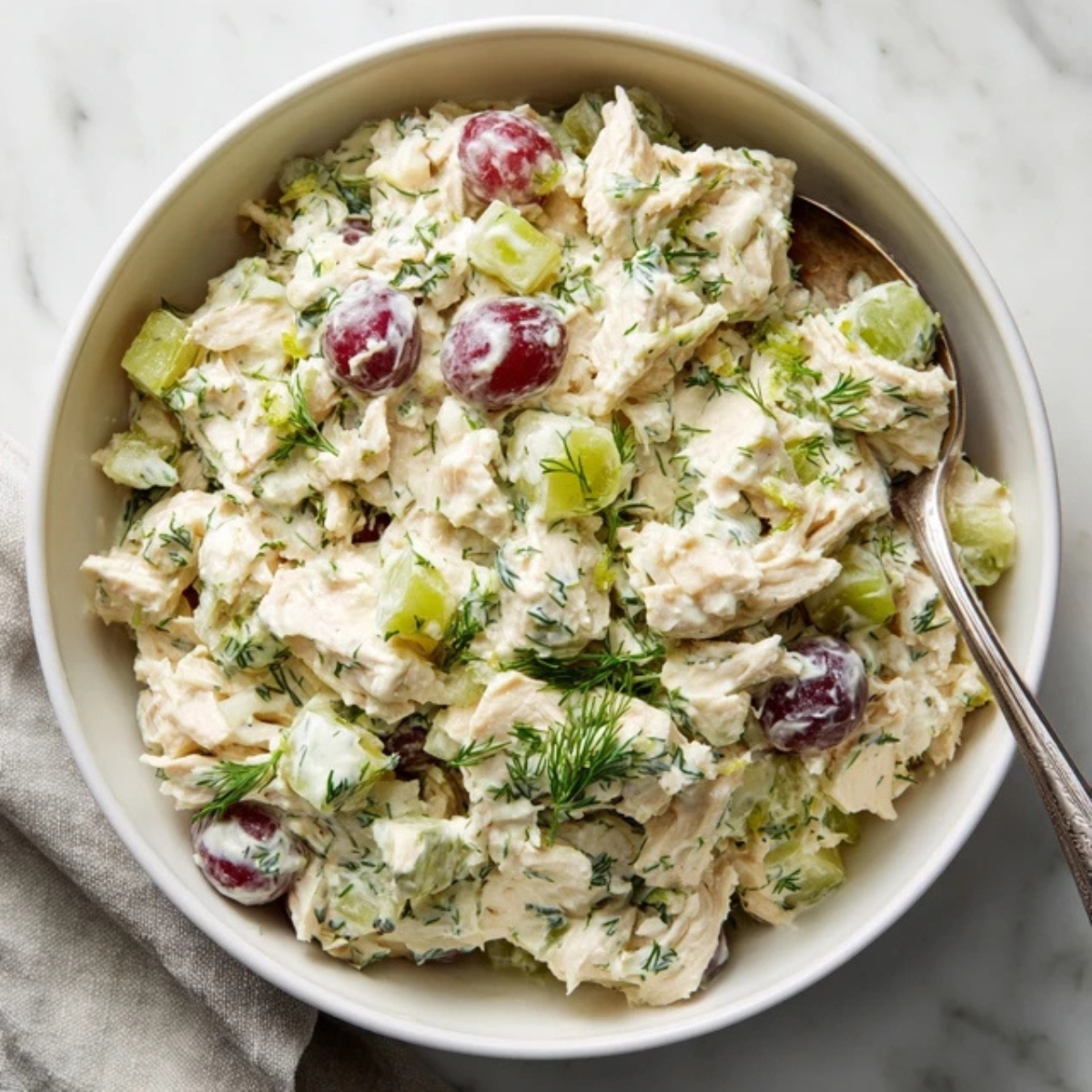 Closeup of creamy homemade chicken salad in a bowl on white counter

