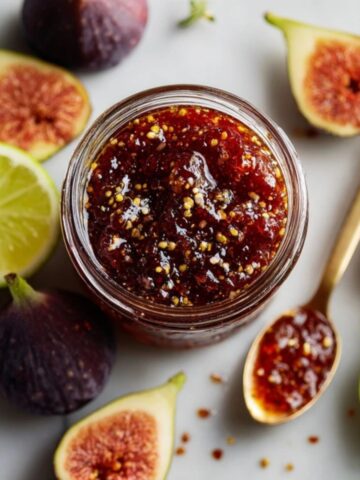 homemade chili fig jam in glass jar with fresh figs and lemon