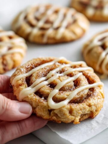 Homemade cinnamon roll cookies with glaze on white kitchen counter