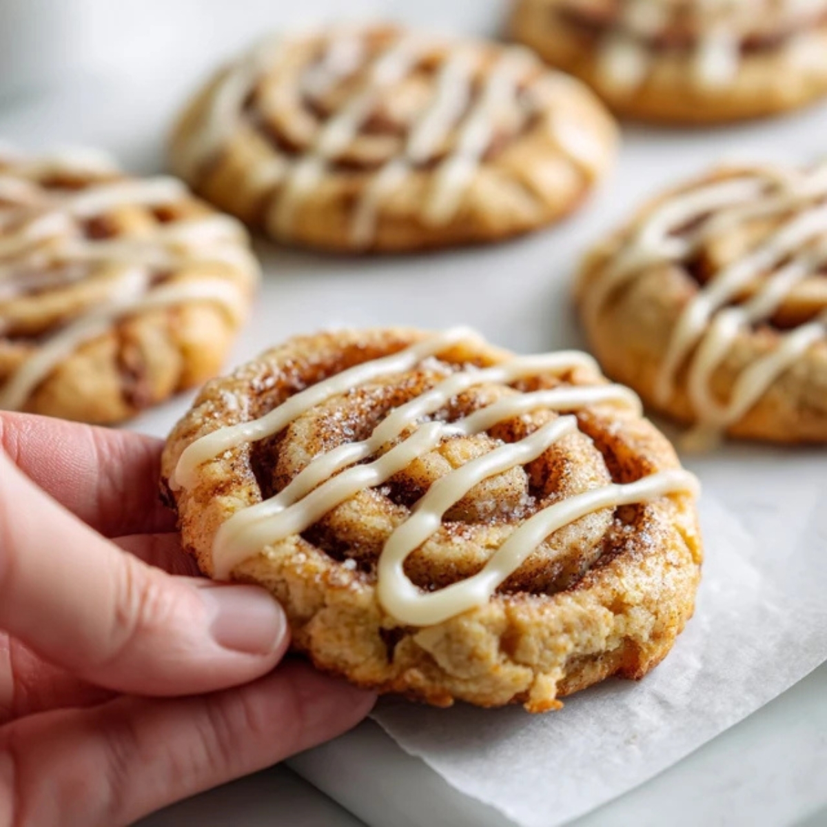 Homemade cinnamon roll cookies with glaze on white kitchen counter