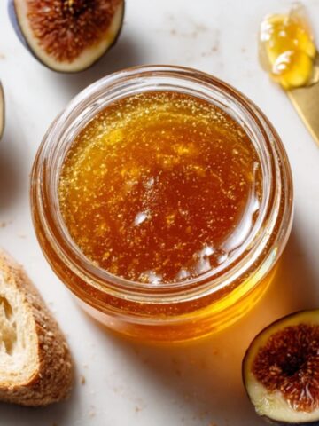 Homemade fig jelly in a glass jar with fresh figs and bread