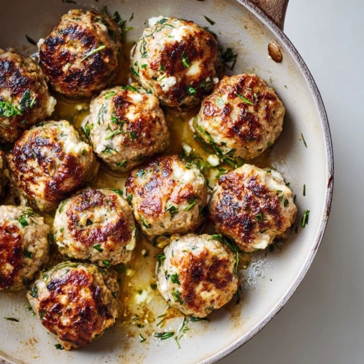 Cooked Greek turkey meatballs in a skillet.