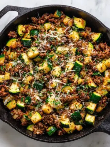ground beef zucchini skillet in cast iron pan on white counter