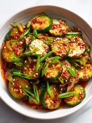 spicy Korean cucumber salad in white bowl with sesame seeds