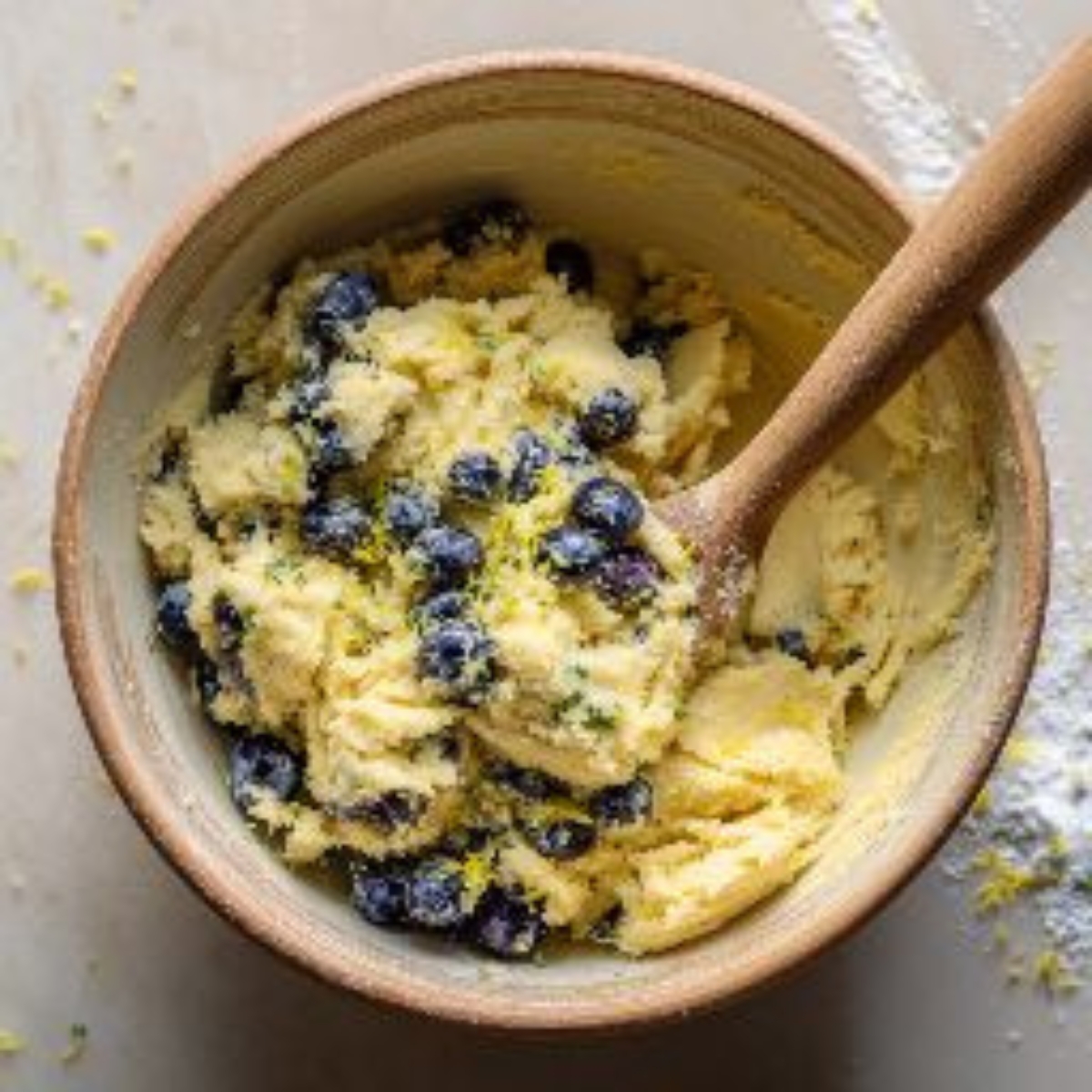 Cookie dough with blueberries and lemon zest in a mixing bowl

