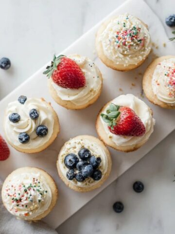 homemade mini cakes with buttercream frosting and sprinkles on white counter