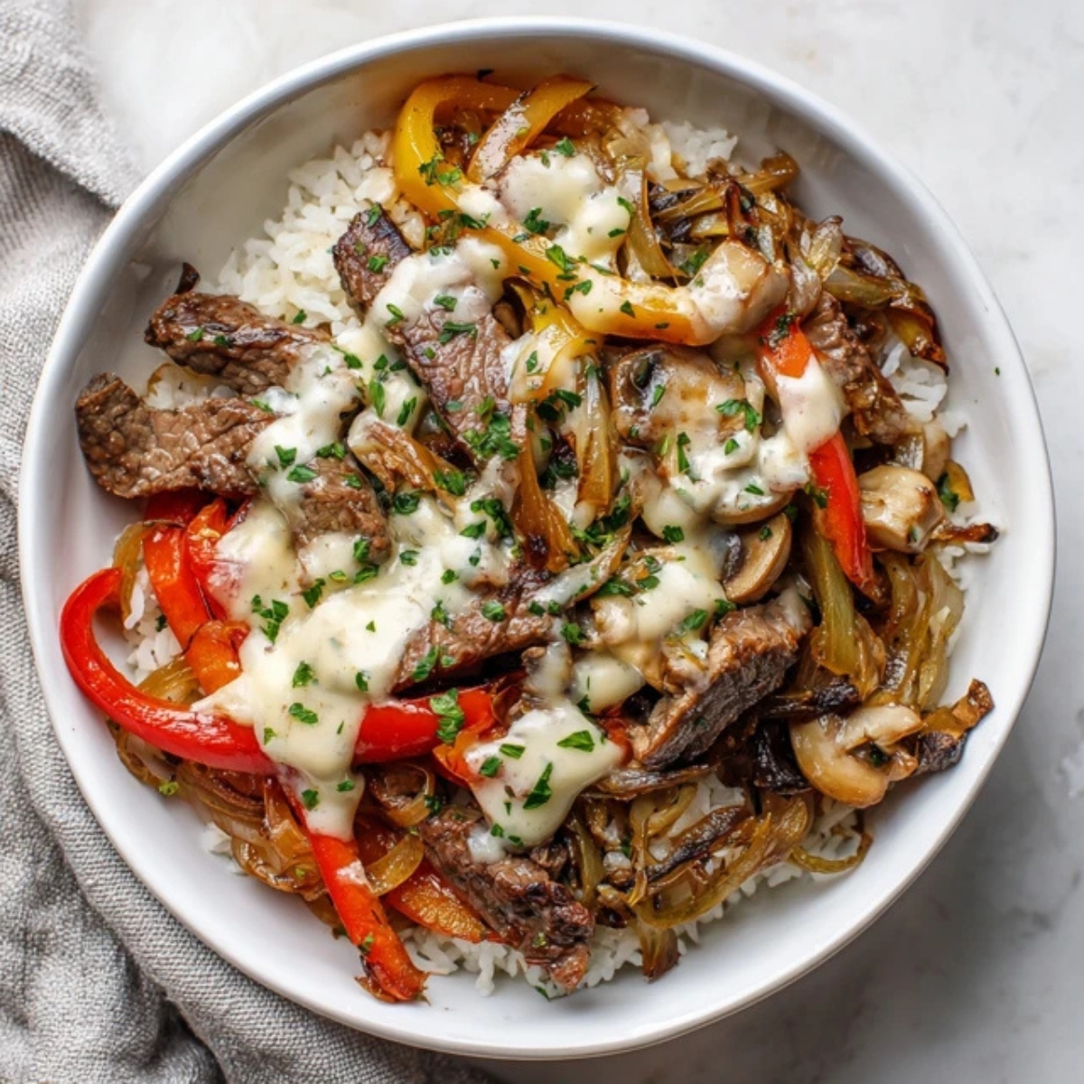 Philly Cheesesteak Bowl with steak, peppers, onions, mushrooms, and melted cheese sauce over rice.
