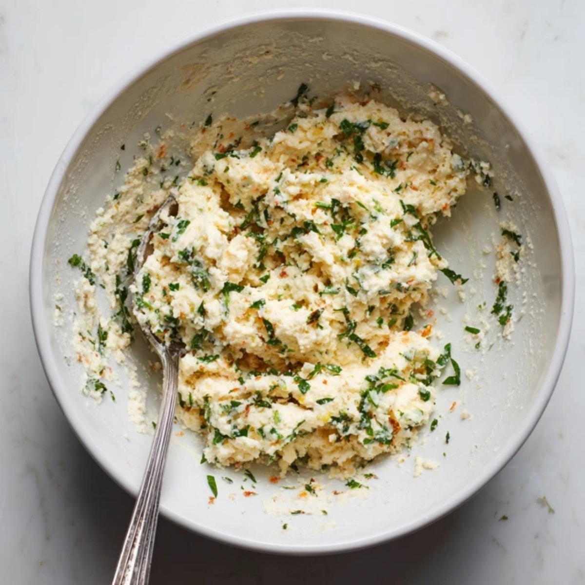 creamy cheese mixture in white bowl with herbs