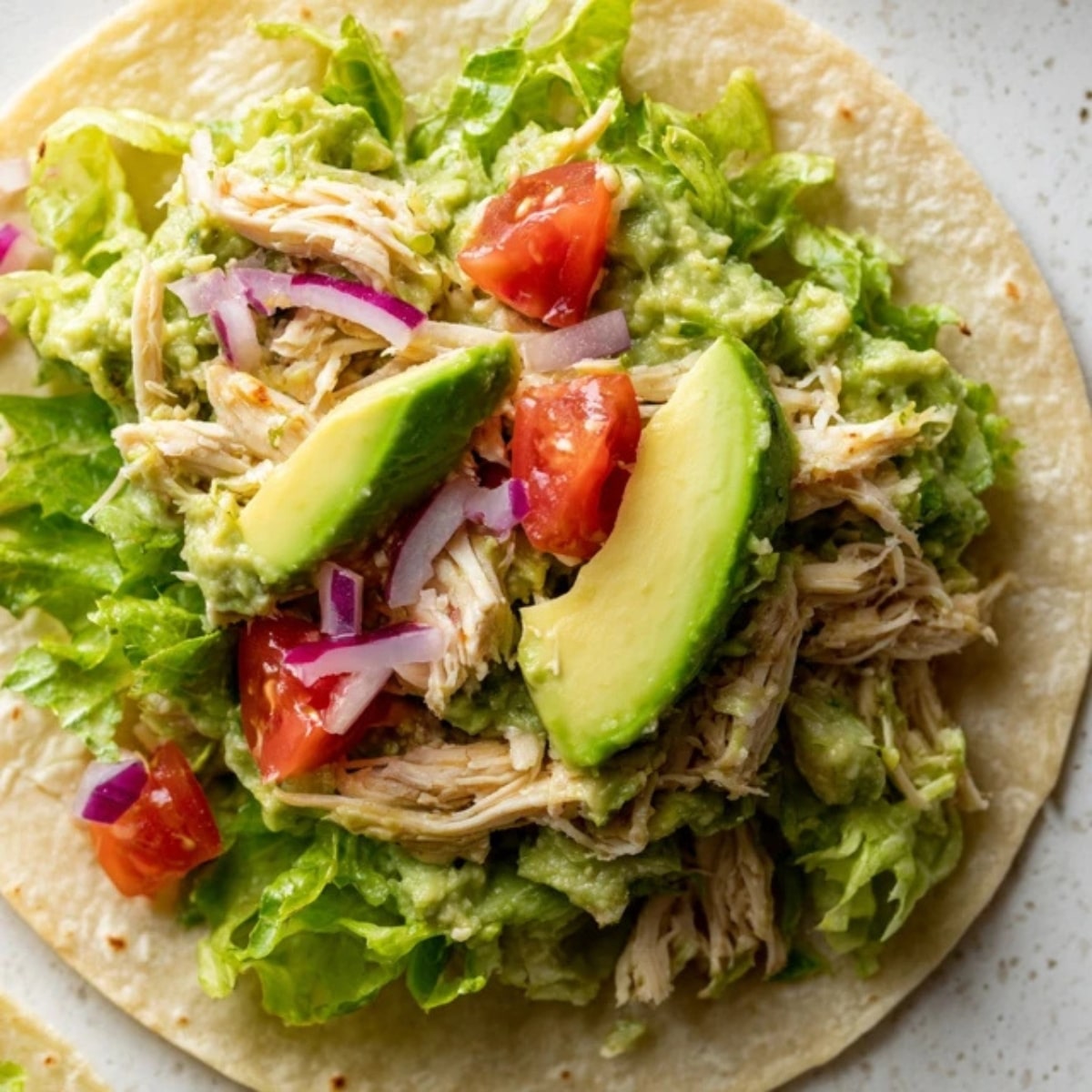 tortilla with avocado spread, chicken, lettuce, tomato, onion