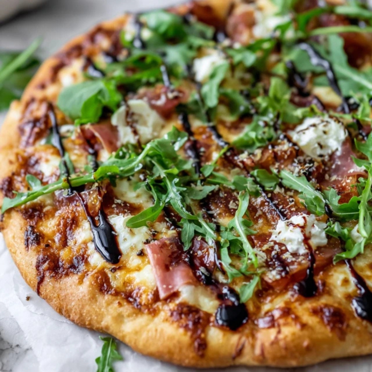 Baked fig prosciutto pizza with arugula and balsamic glaze.