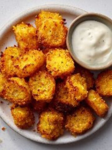 Golden crispy yellow squash tots on a plate.