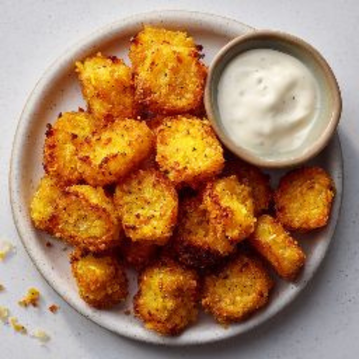 Golden crispy yellow squash tots on a plate.