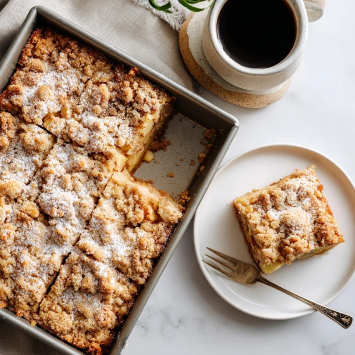 Homemade apple crumb cake with golden buttery topping on white kitchen counter