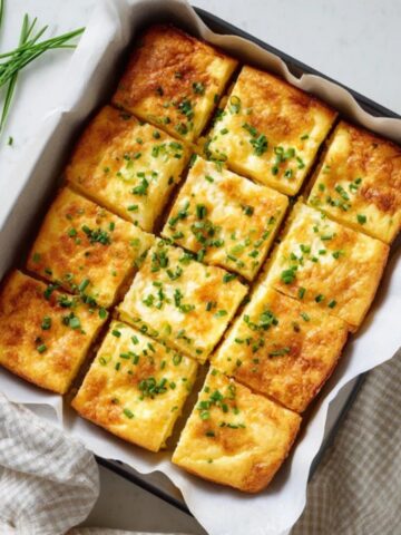 Fluffy baked cottage cheese eggs cut into squares on white counter