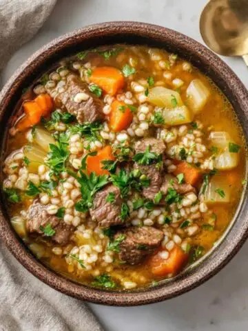 Hearty beef barley soup instant pot recipe in bowl with vegetables and barley
