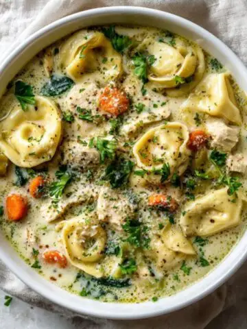 creamy chicken tortellini soup in bowl with spinach and parmesan