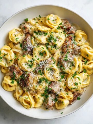 creamy steak tortellini with garlic parmesan sauce in white bowl