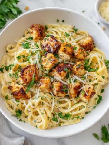 Garlic butter chicken bites with creamy parmesan pasta in white bowl