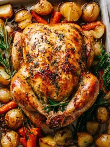 juicy golden herb roasted chicken with vegetables on a pan