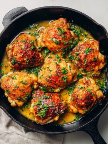 crispy honey dijon chicken thighs in skillet with golden glaze