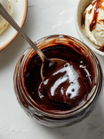 rich homemade hot fudge sauce in glass jar with spoon