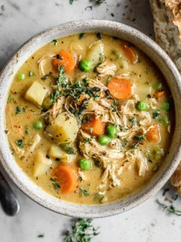Creamy Instant Pot Chicken Pot Pie Soup in a bowl with bread on the side