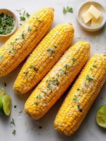 buttery Instant Pot corn on the cob with herbs and lime wedges