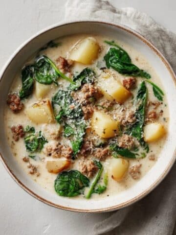 Creamy Italian Sausage and Potato Soup in a rustic bowl on white counter