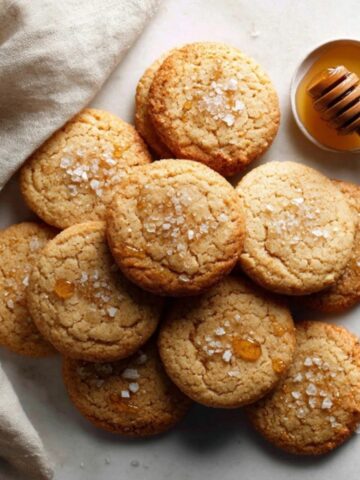 Chewy salted honey cookies with sea salt and honey drizzle on kitchen counter