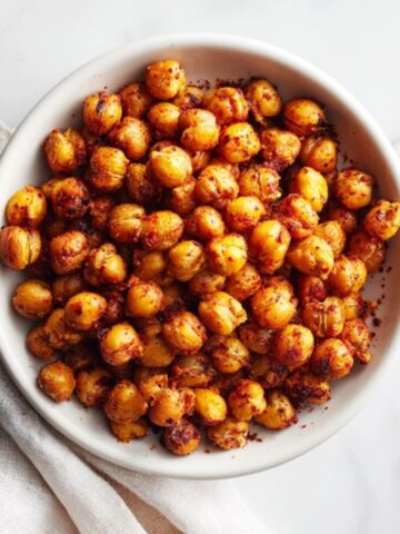 Crispy spicy roasted chickpeas in a white bowl on kitchen counter