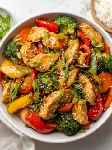 Homemade teriyaki chicken stir fry with vegetables and rice in white bowl