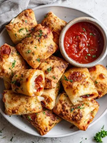 Crispy air fryer pizza rolls with melted cheese and pepperoni on white counter