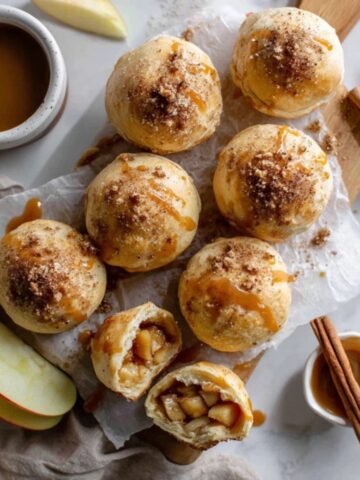 flaky apple pie bombs with caramel drizzle on white counter