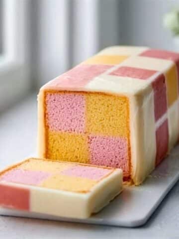 Homemade Battenburg Cake with pink and yellow checkerboard pattern on white kitchen counter