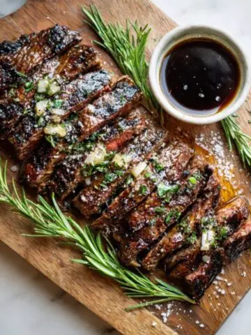 Juicy sliced bavette steak with garlic butter and herbs on a white kitchen counter