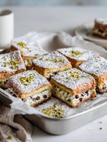 Homemade cannoli squares with ricotta filling and powdered sugar on white kitchen counter