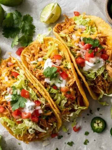 Cheesy chicken tacos with toppings on white kitchen counter