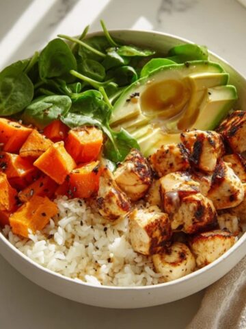 Healthy chicken bowls with sweet potatoes and maple dijon glaze on a white kitchen counter