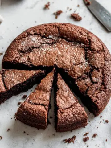 Homemade chocolate brownie cake with crackly top on white kitchen counter