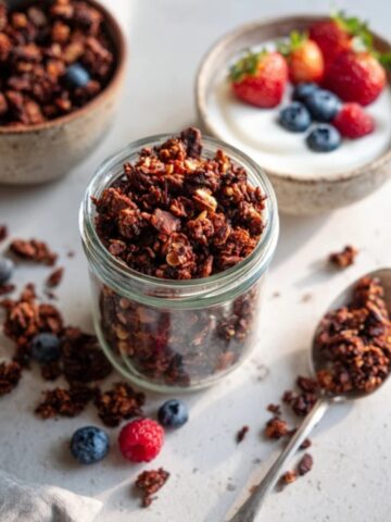homemade chocolate granola in jar with yogurt and berries