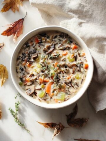 Creamy autumn wild rice soup with mushrooms and carrots in a cozy fall setting