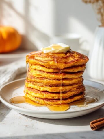 Fluffy pumpkin pancakes stacked with maple syrup and butter