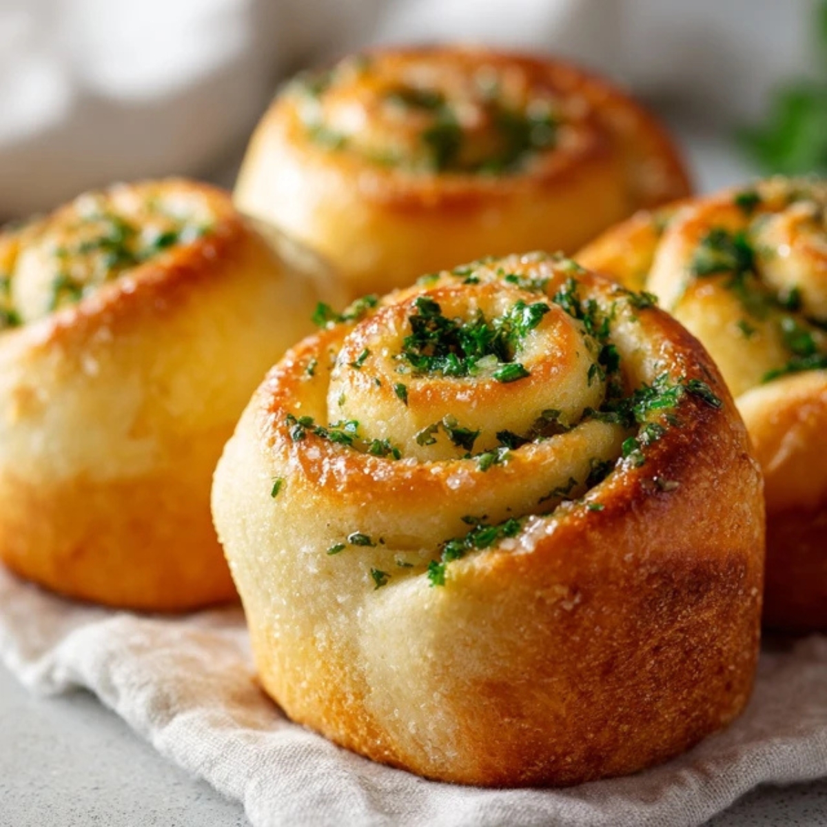 Soft homemade garlic swirl rolls brushed with melted butter and parsley on a white kitchen counter