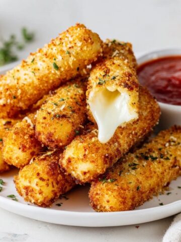 Homemade crispy mozzarella sticks with gooey cheese pull and marinara dip