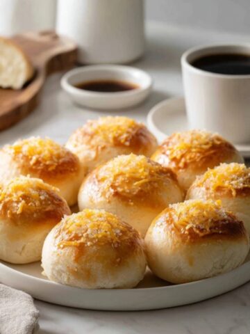 Soft homemade ensaymada bread with butter and cheese on white kitchen counter