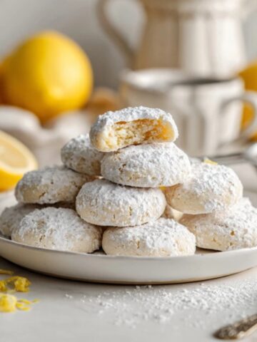 Buttery lemon meltaways cookies dusted with powdered sugar on white plate