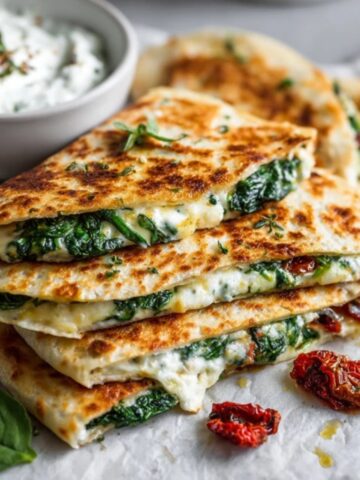 Homemade Mediterranean spinach feta quesadillas with tzatziki dip on white counter