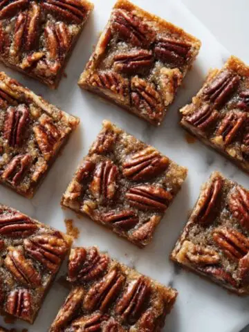 gooey pecan pie bars with buttery shortbread crust on white kitchen counter