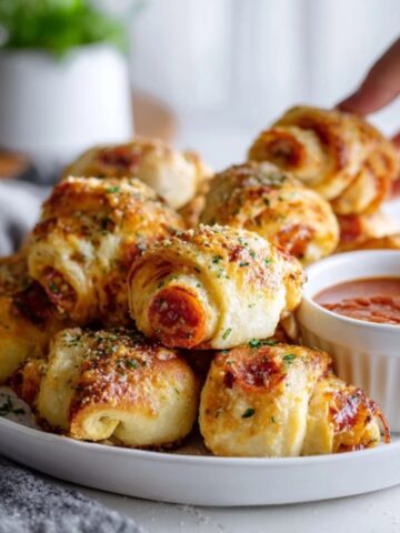 Homemade pepperoni pizza roll-ups with melted cheese and pizza sauce